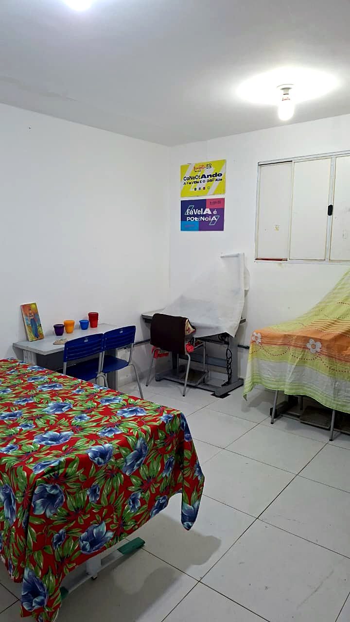 Sala da incubadora de empreendimentos da beleza do Espaço Dandaras para Sempre, com mesas, cadeiras e cartazes na parede.